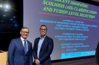 Image of Drs. Lenke and Beauchamp in front of a large screen with a presentation of idiopathic scoliosis classification and fusion level selection